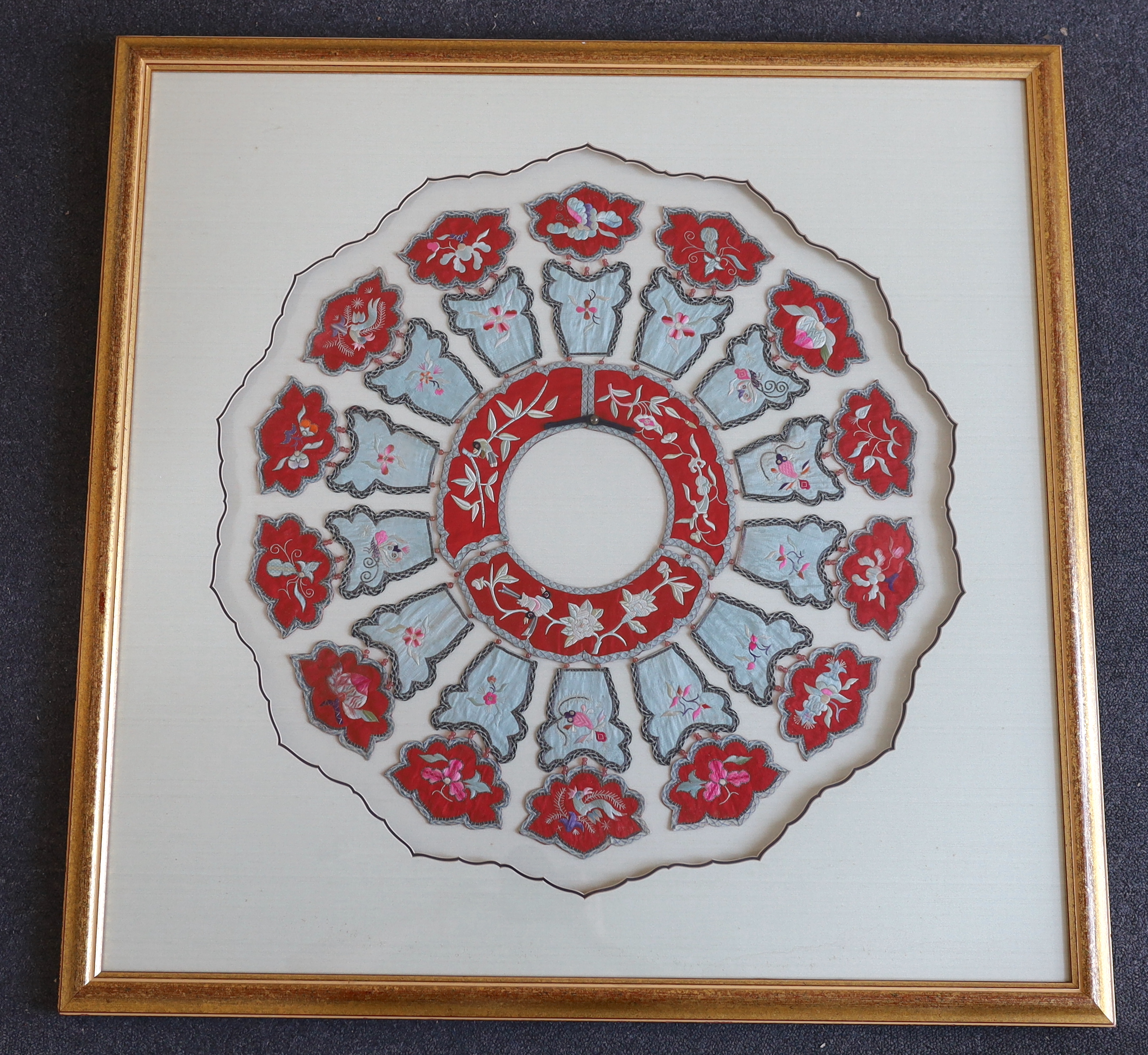 A large early 20th century Chinese silk embroidered collar, made with fourteen decorative and embroidered hanging panels attached to a circular central collar with bead attachments, set within an ornate mount and framed,